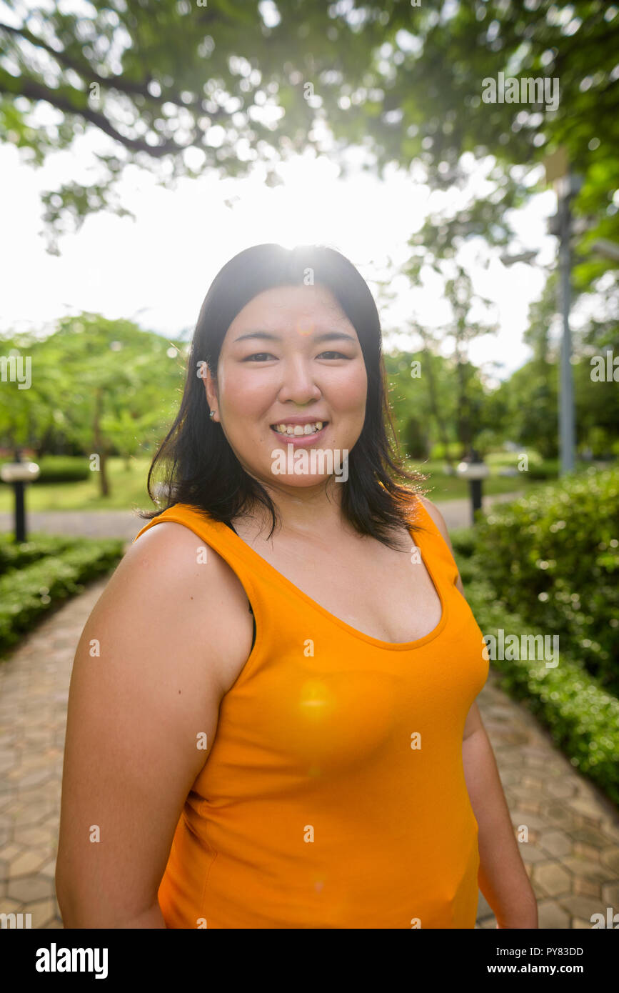 Belle asiatique surpoids woman smiling in park avec lens flare Banque D'Images