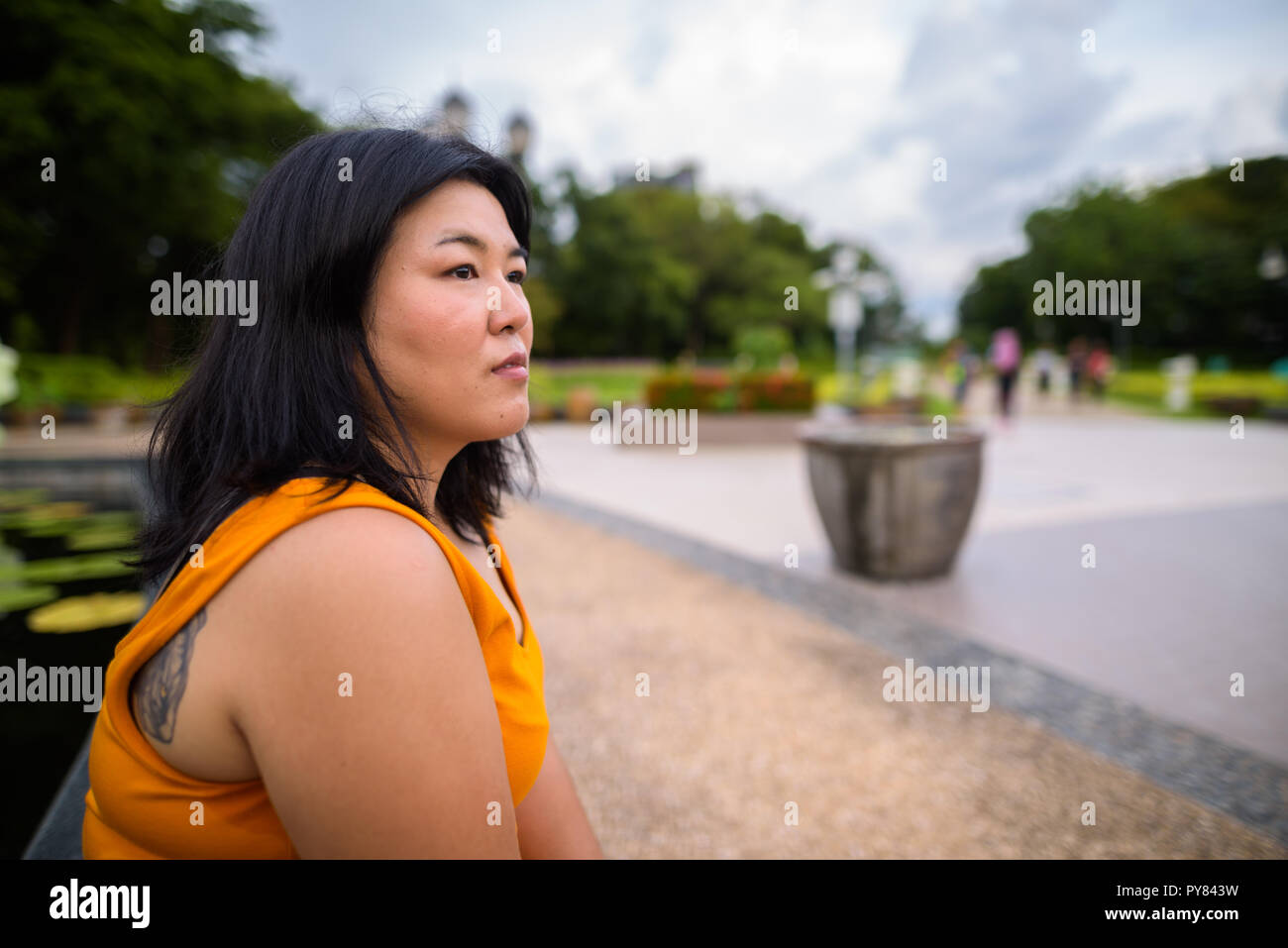 Voir le profil de l'excès de Asian woman sitting et penser dans park Banque D'Images