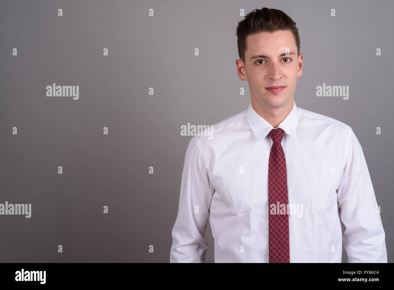 Portrait of young handsome businessman contre l'arrière-plan gris Banque D'Images