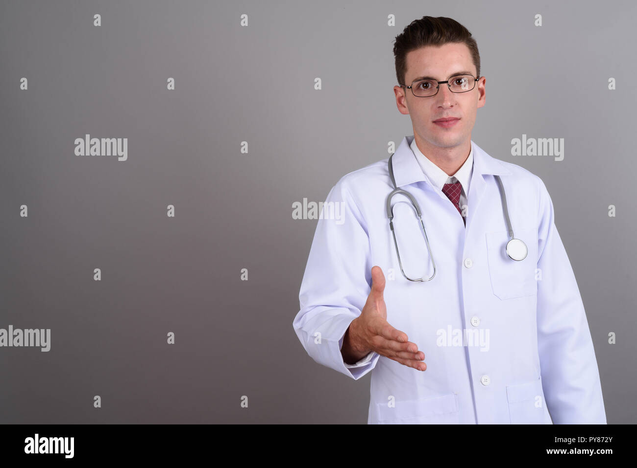Jeune homme séduisant médecin poignée donnant et looking at camera Banque D'Images