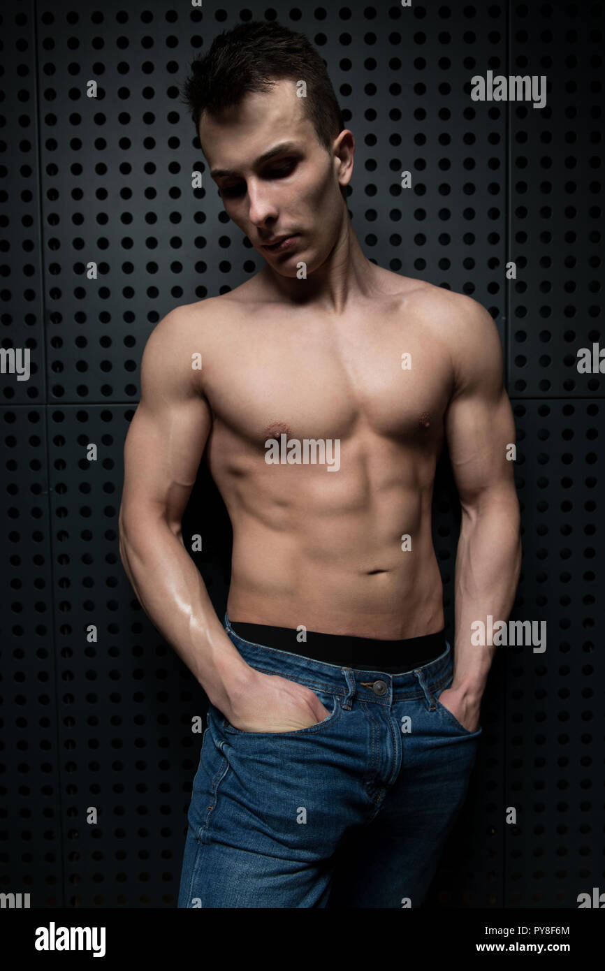 Portrait d'un jeune homme en bonne forme physique montrant son corps bien formé tout en portant un jean bleu - Remise en forme musculaire Bodybuilder athlétique arrière Model Posing Banque D'Images