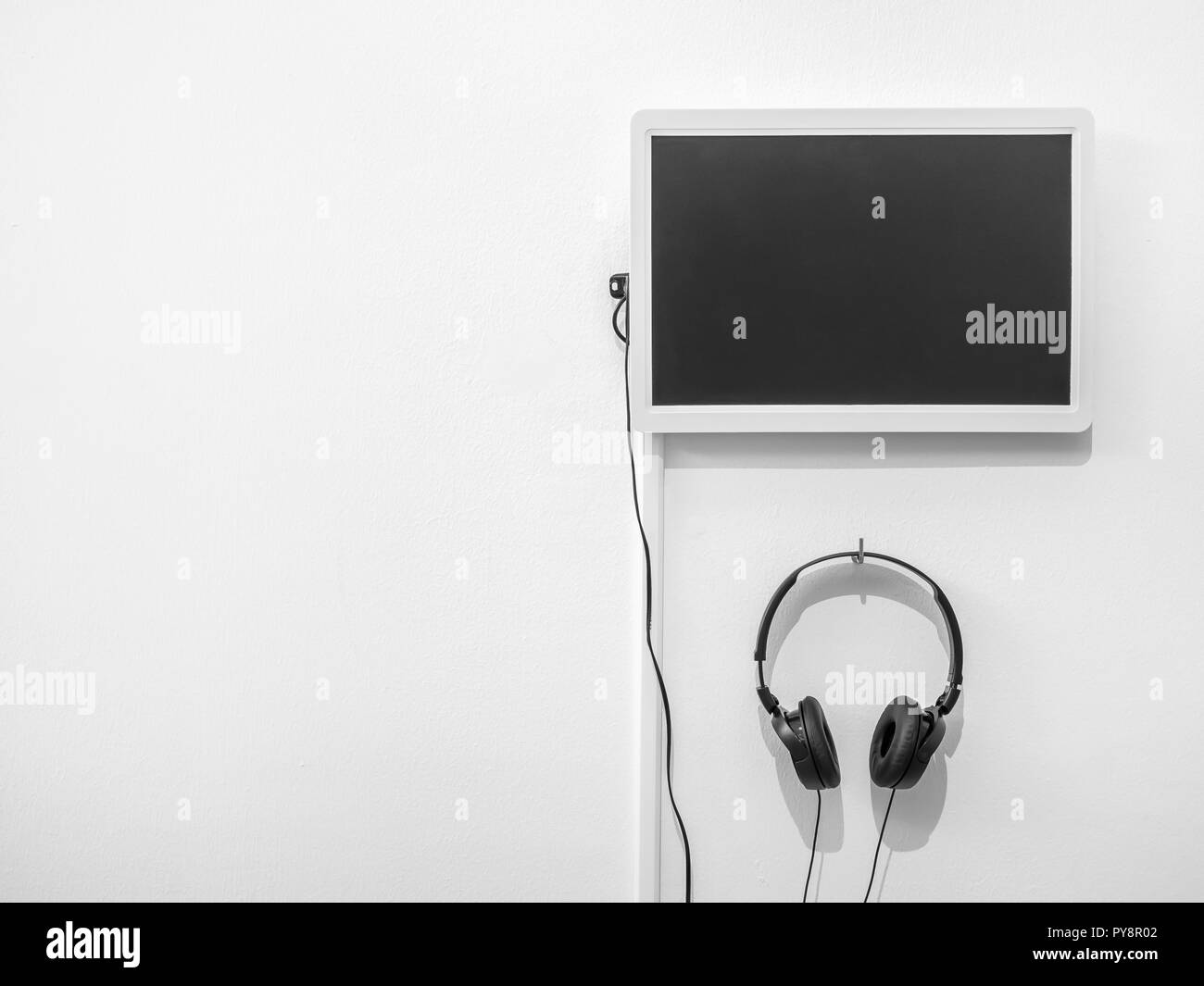 Moniteur blanc et casque accroché sur mur blanc pur avec l'exemplaire de l'espace. Banque D'Images