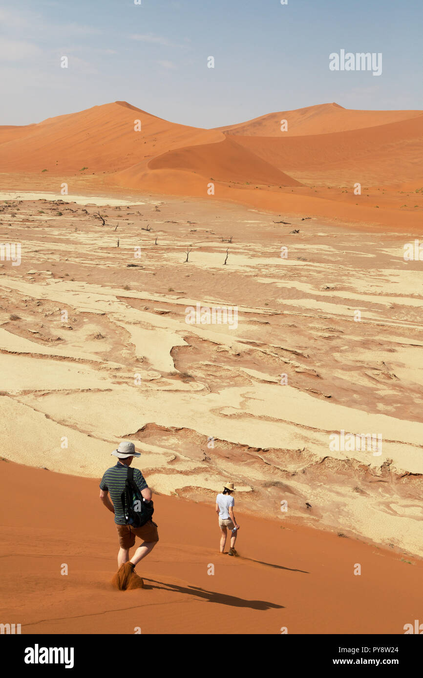 Namibie - Voyage d'un couple descending les dunes de sable de Deadvlei, Sossusvlei, Désert du Namib, Namib-Naukluft National Park, Afrique Namibie Banque D'Images