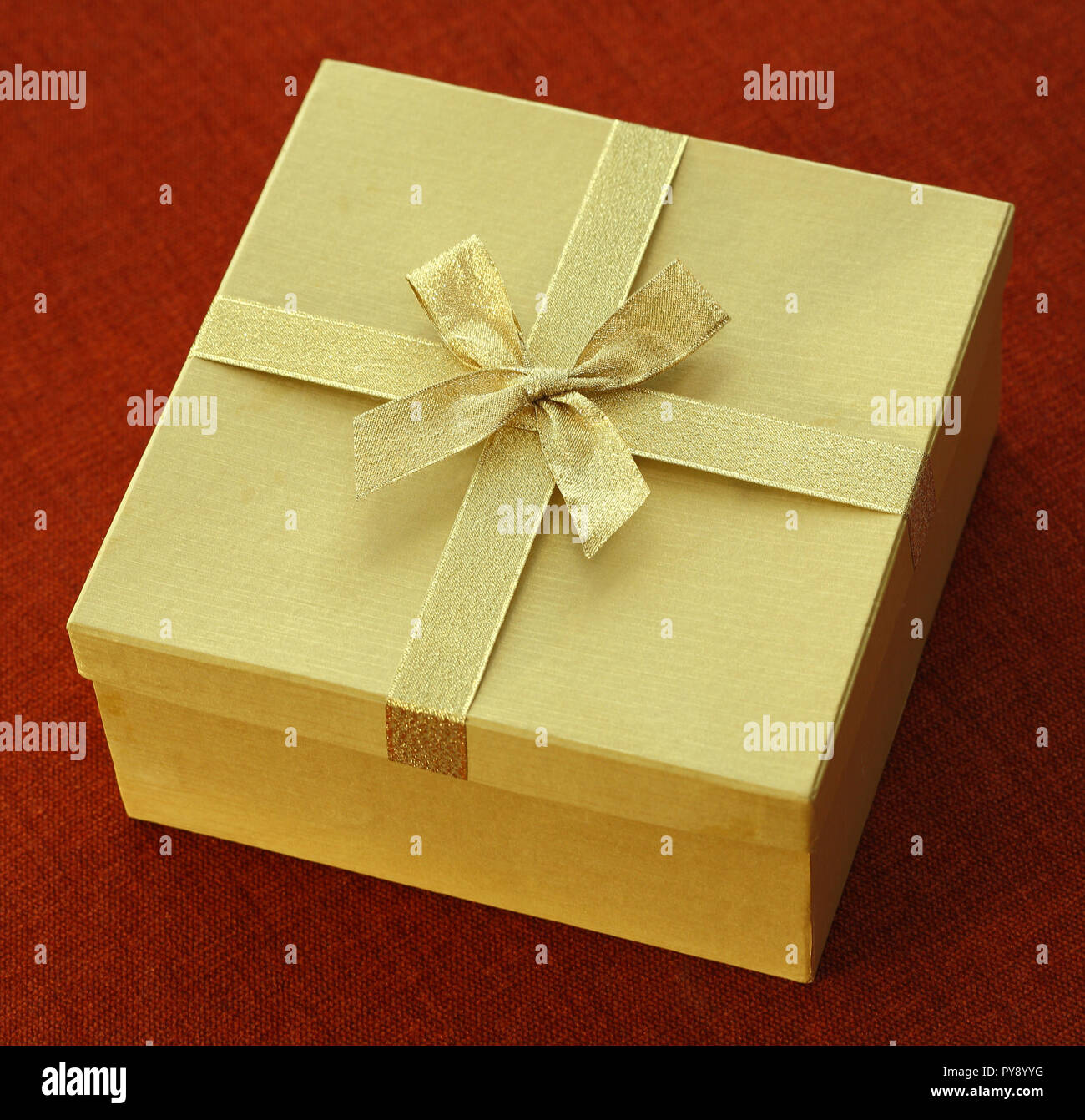 Boîte cadeau doré avec papillon sur fond de tissu noir Banque D'Images