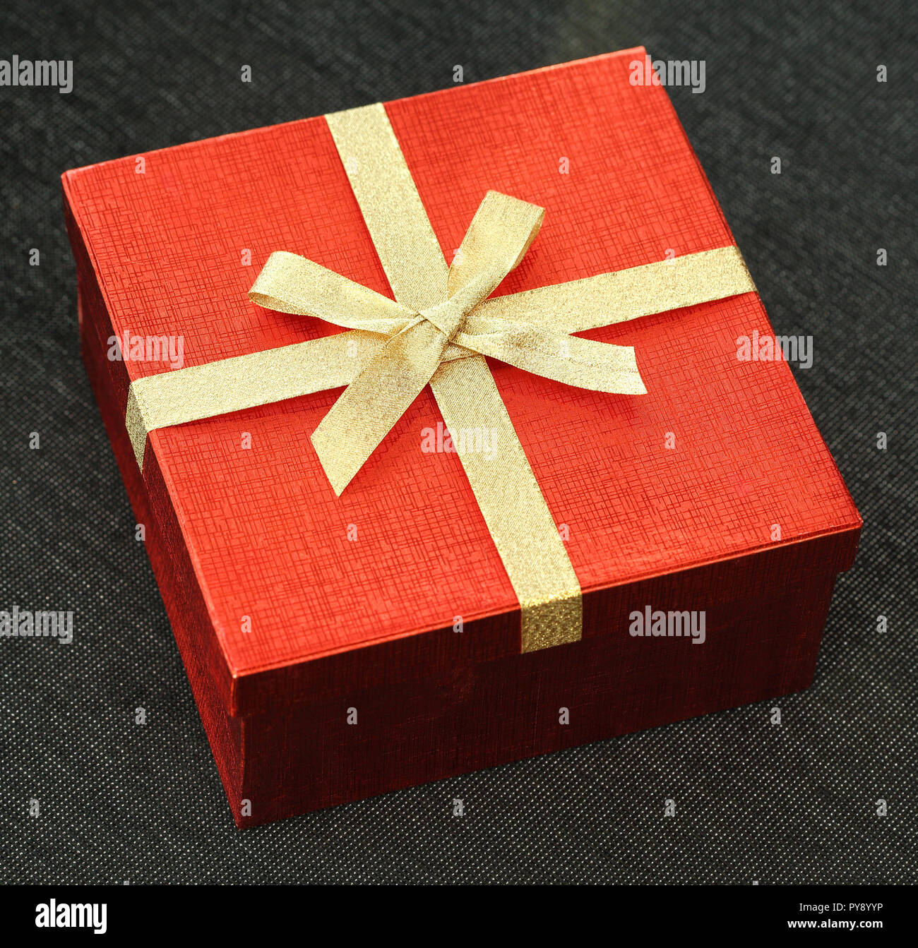 Boîte cadeau rouge avec papillon sur fond de tissu noir Banque D'Images