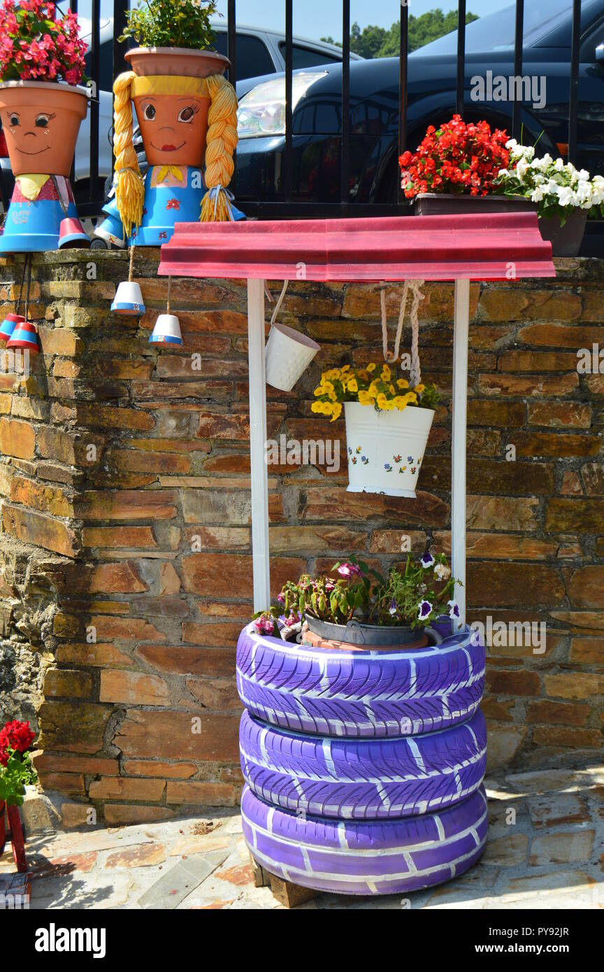 Pots pittoresque décoré comme deux jeunes Asturiens à côté d'un puits d'eau  également décoré avec du violet de pneus de Taramundi, Asturias, Espagne.  L'art, l'histoire Photo Stock - Alamy