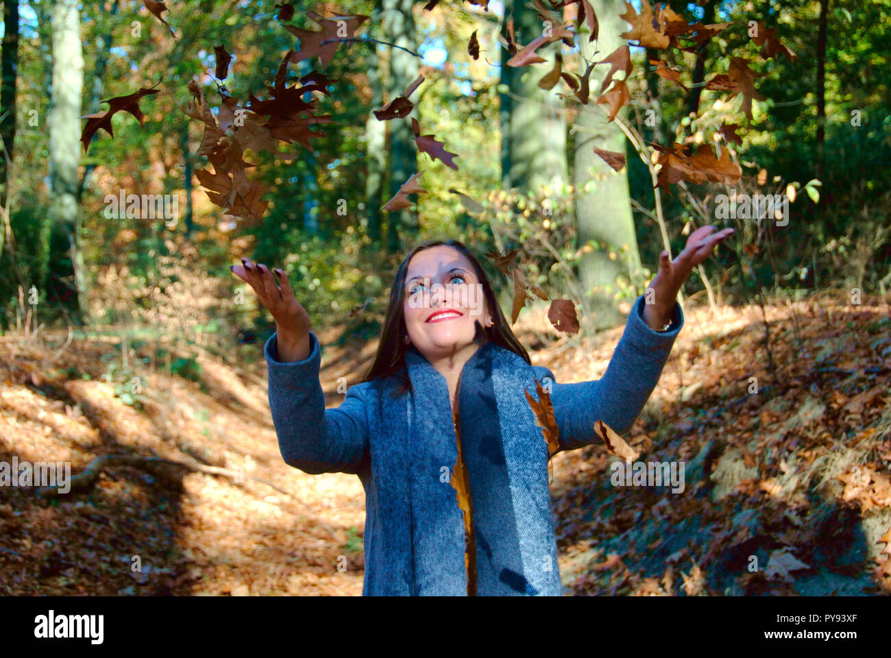 Une belle femme joue avec les feuilles dans la forêt de Duisburg en Allemagne, tandis que la saison des changements à l'automne Banque D'Images