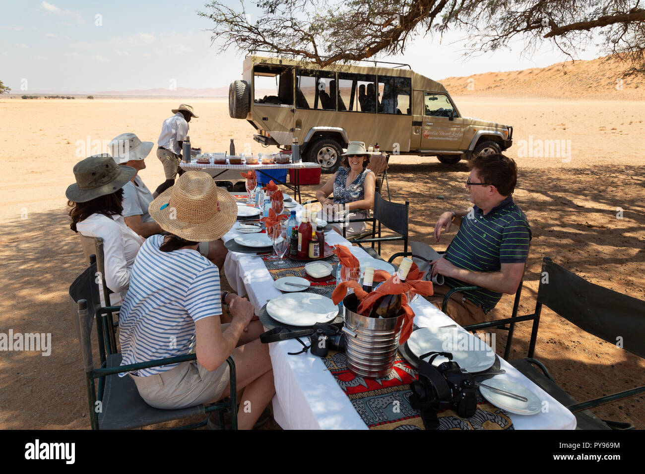 Namibie - Les touristes Les touristes ayant un repas dans le désert de Namibie lors d'un safari, avec leur guide, Désert du Namib, Namibie, Afrique du Sud Banque D'Images