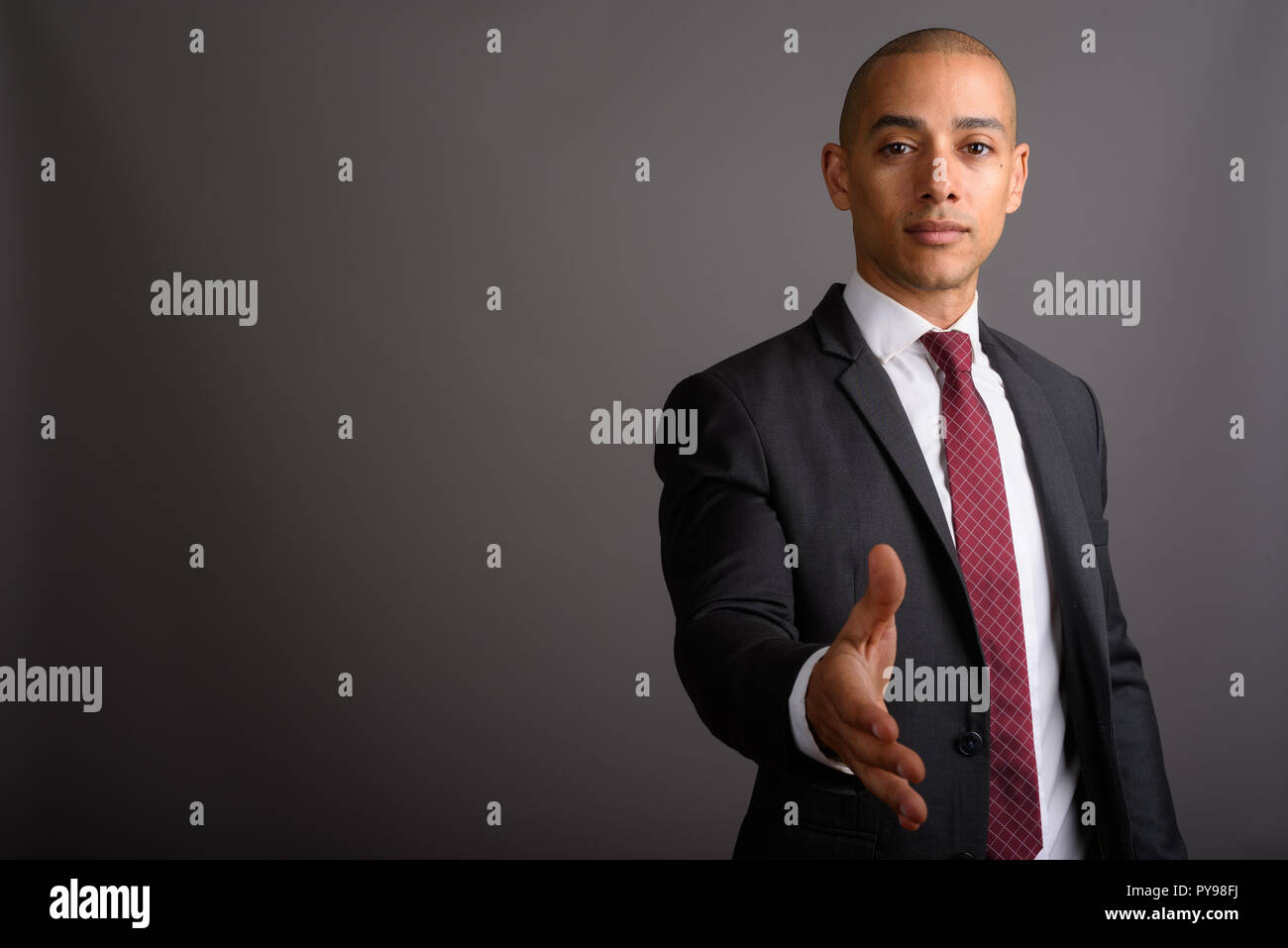 Handsome bald businessman giving handshake et looking at camera Banque D'Images