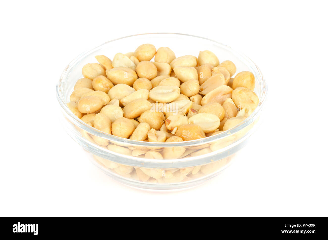 Grillées et salées arachides dans bol en verre. Bombardé Arachis hypogaea, également appelé ou arachide goober, utilisé comme un en-cas. Macro photo alimentaire isolé. Banque D'Images