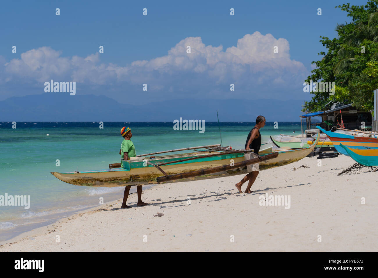 Deux pêcheurs philippins récupérer leur Bancart Lambug,bateau de pêche,plage,Cebu Philippines,Badian Banque D'Images