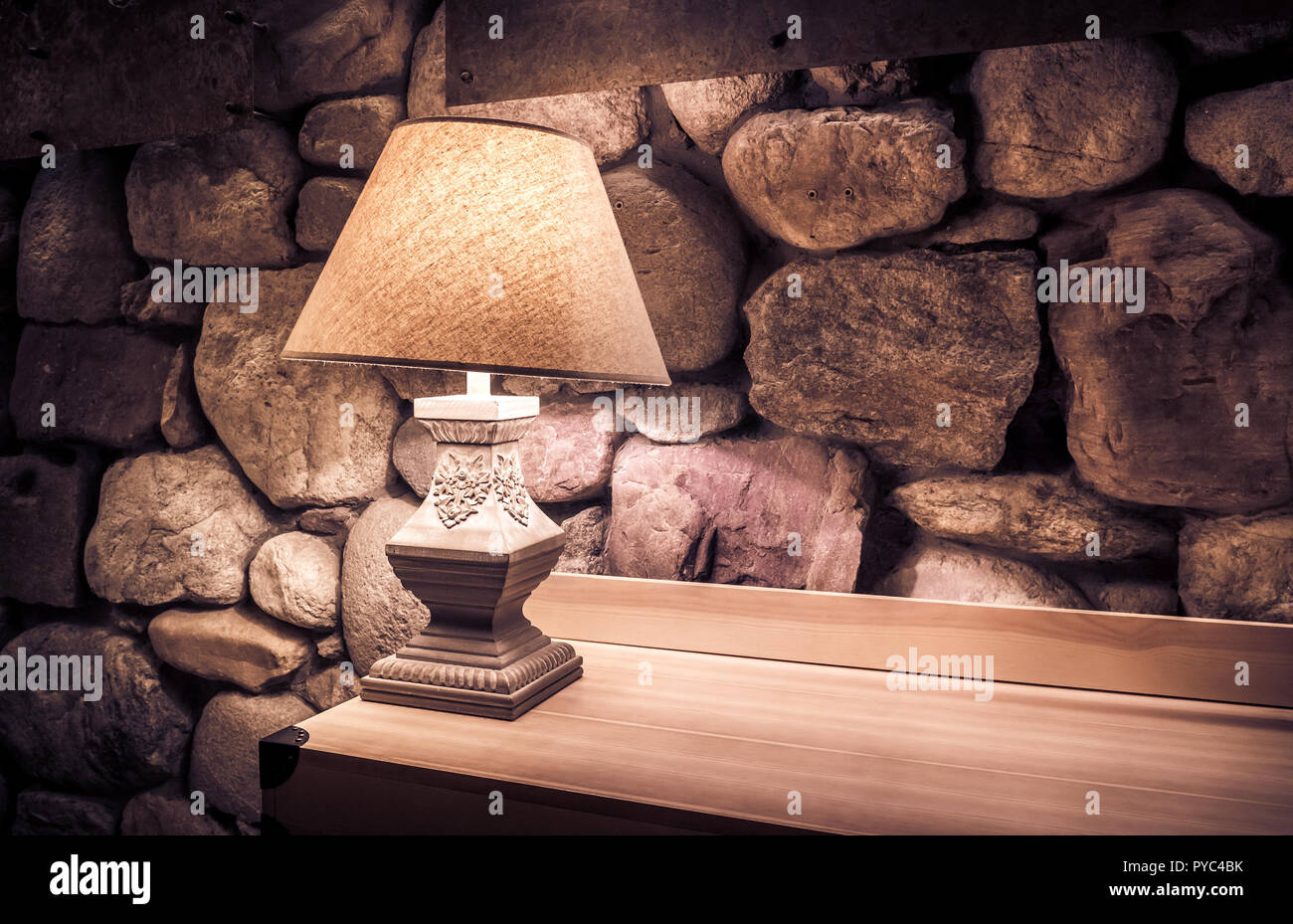 Mur de pierre éclairés par la lampe sur table en bois élégant Banque D'Images