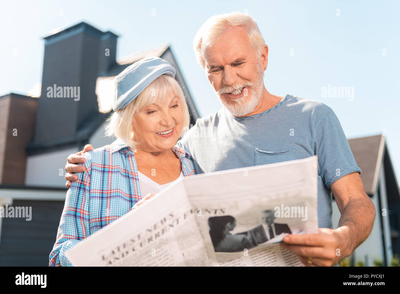 Couple retraités lire leur journal du matin ensemble en dehors de chambre Banque D'Images