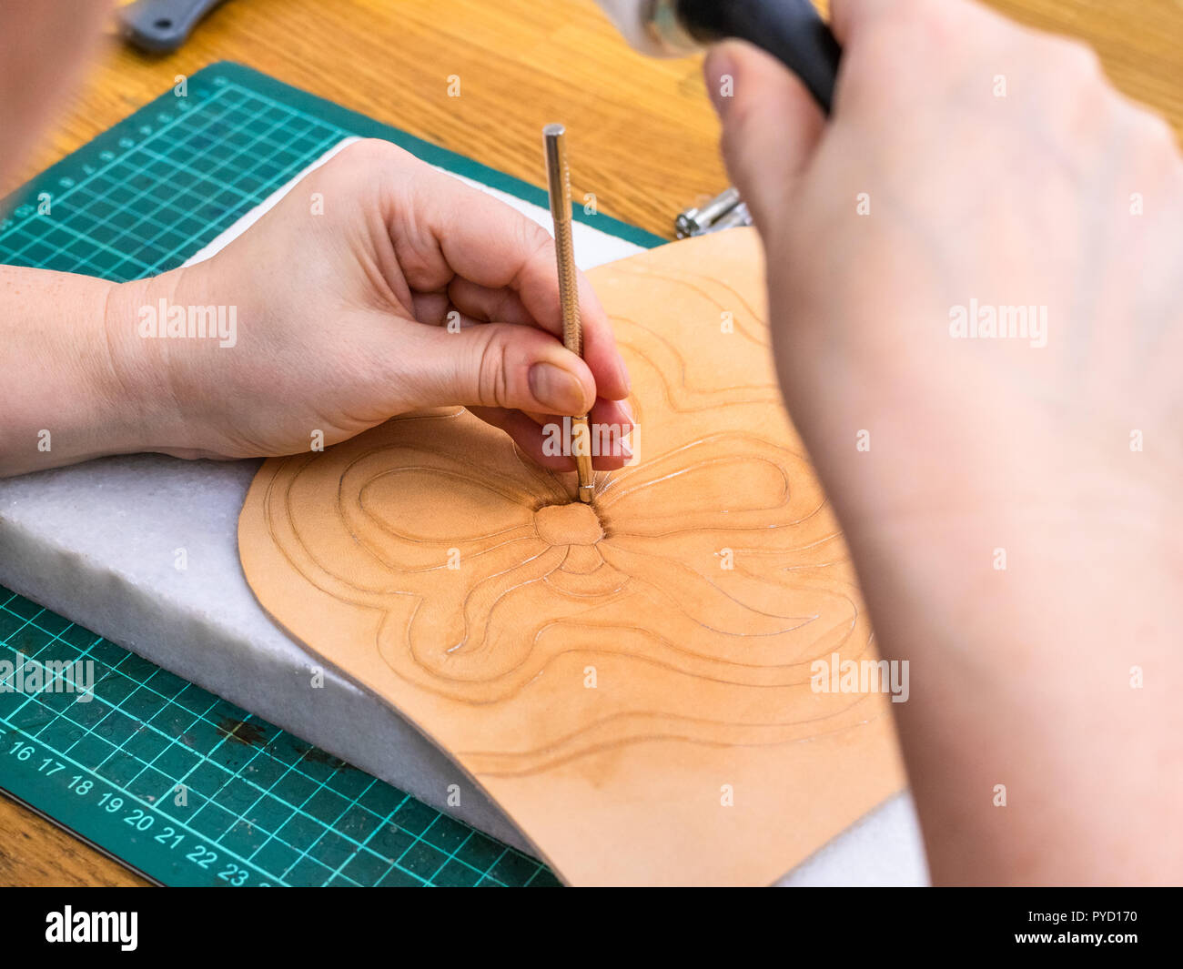 Atelier de la Sac en cuir sculpté - artisan stamps l'image de fleur sur la surface du cuir tanné végétale rugueuse avec l'outil d'estampage et Banque D'Images