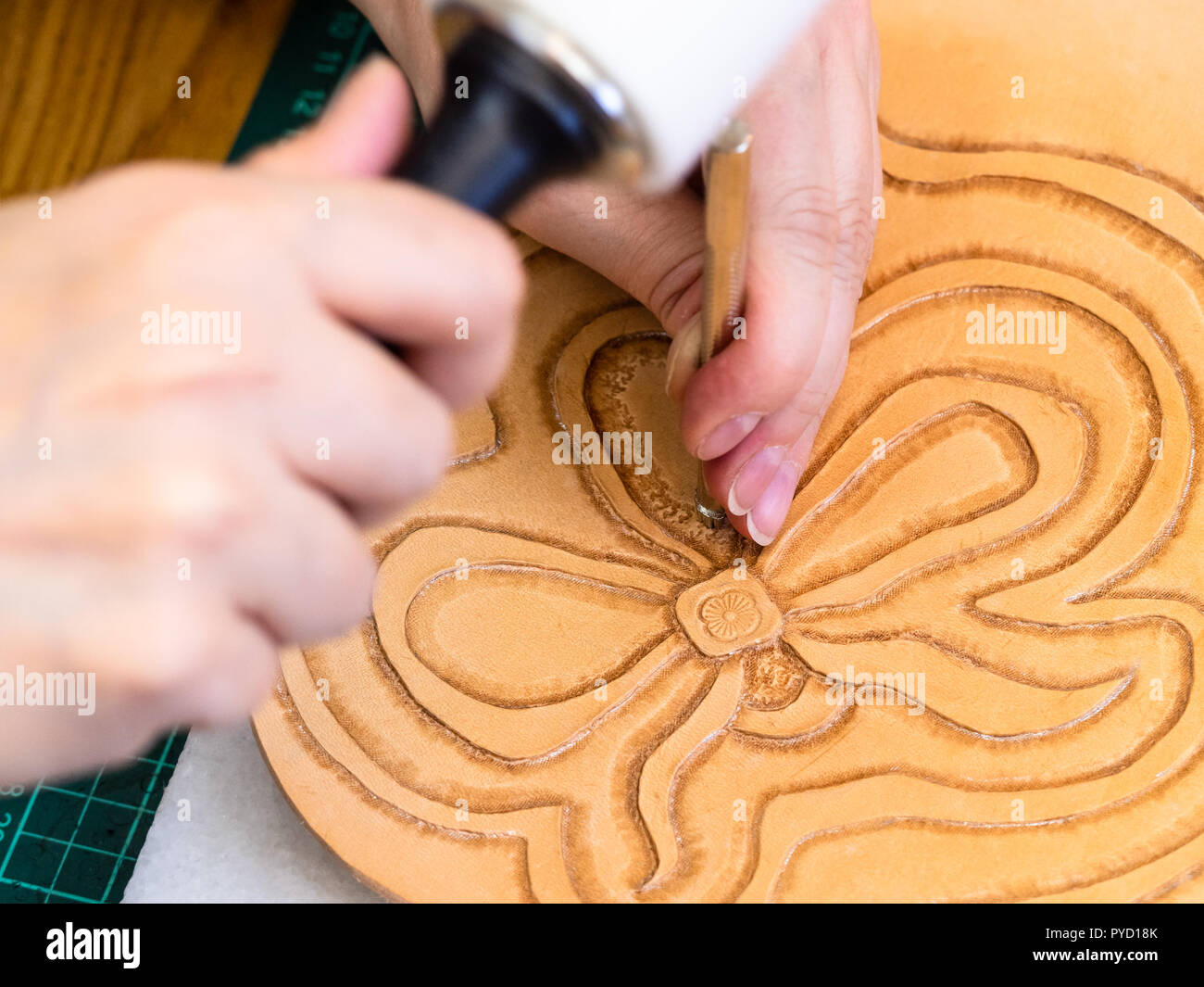 Atelier de la Sac en cuir sculpté - artisan stamps la fleur sur la surface du cuir tanné végétale rugueuse avec l'outil d'estampage et mallet Banque D'Images