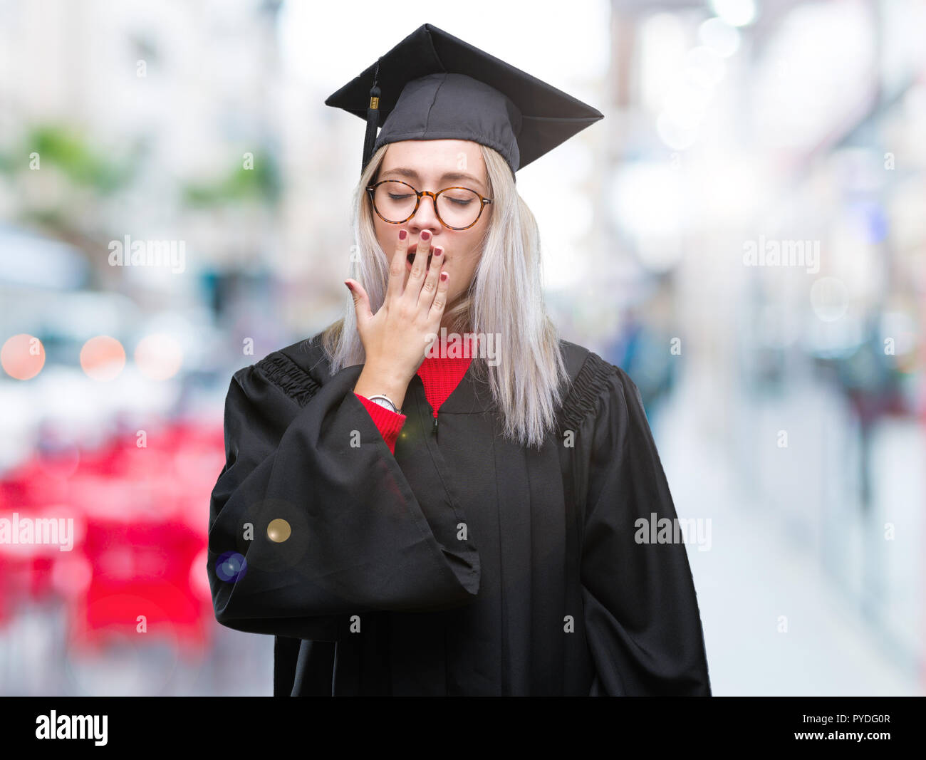 Young blonde woman wearing graduate uniforme sur fond isolé ennuyer le bâillement fatigué couvrant la bouche avec la main. Agité et somnolence. Banque D'Images