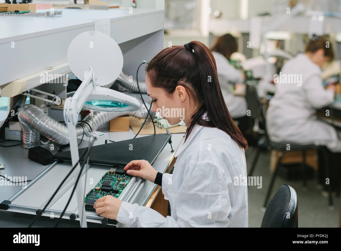 Une femelle technicien vérifie un conseil de l'ordinateur dans une usine. L'occupation professionnelle. Spécialiste hautement qualifié dans le domaine de l'assemblage d'ordinateurs o Banque D'Images