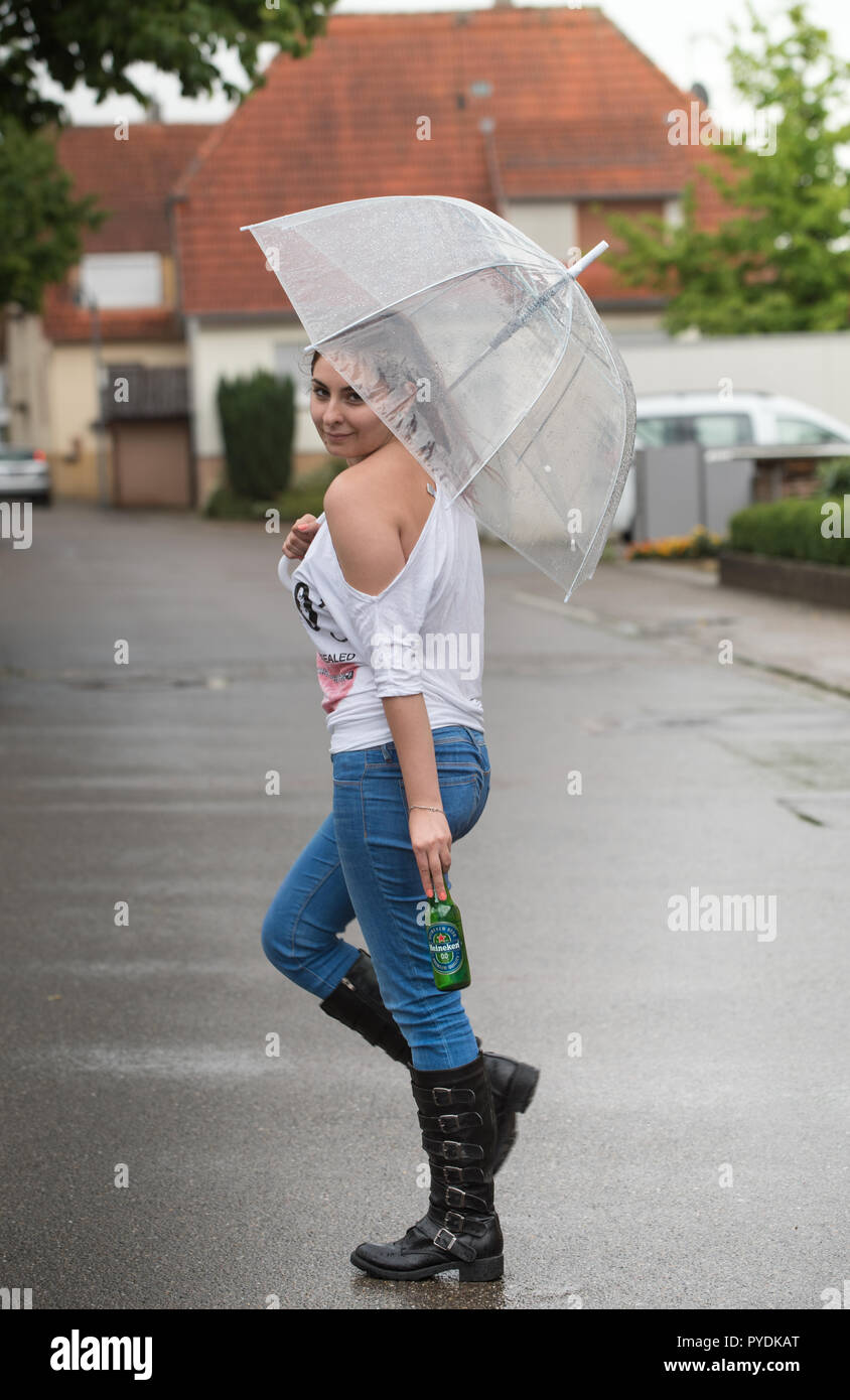 Une jeune femme avec un parapluie dans sa main des danses sous la pluie  tenant une bouteille de bière Heineken Photo Stock - Alamy