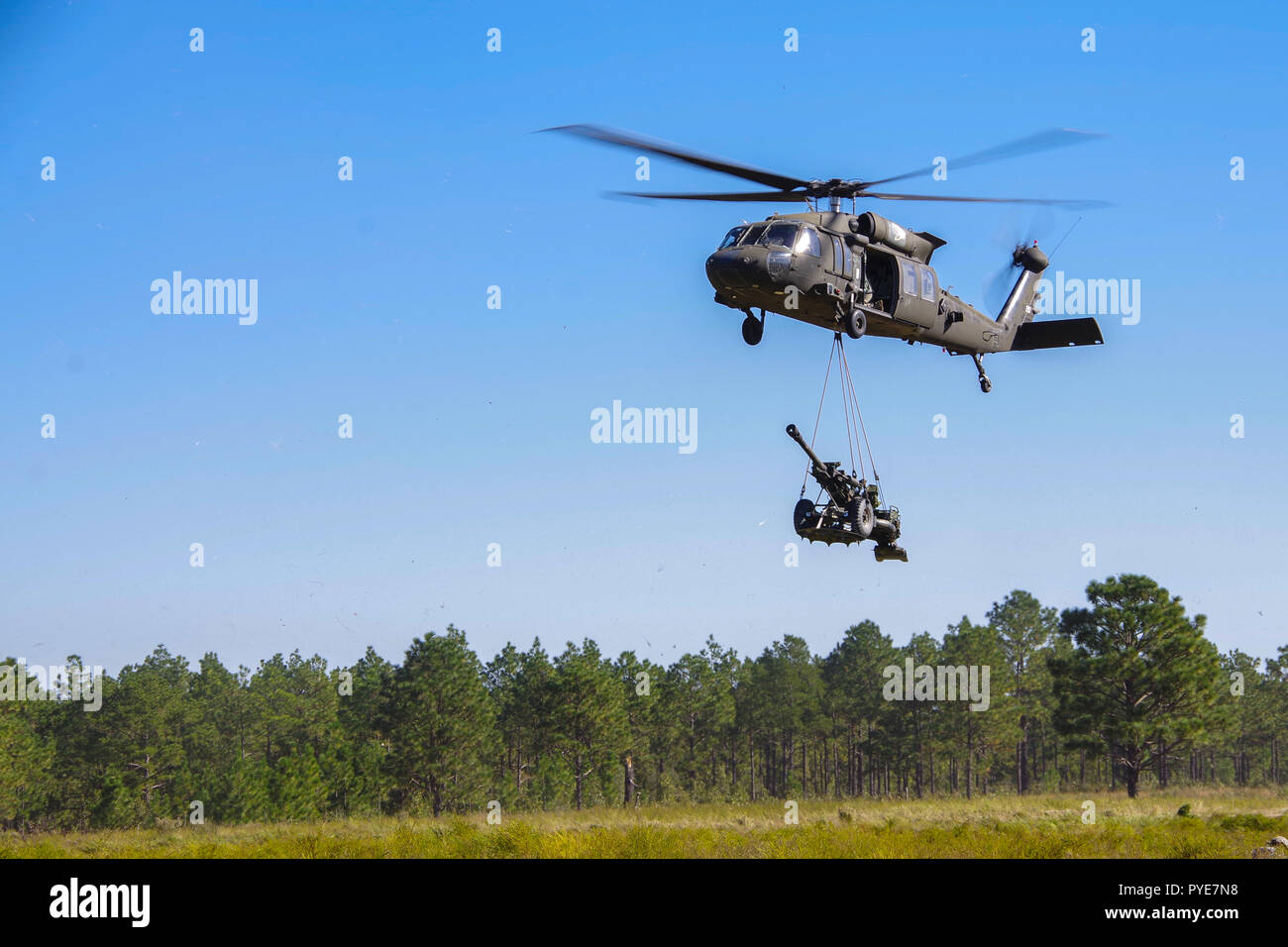 Un hélicoptère Blackhawk UH-60 piloté par les aviateurs de la société C, 2-82, 82e Régiment d'aviation Brigade de l'aviation de combat sling-charge un obusier M119A3 appartenant à la batterie Alpha, 1er Bataillon, 319e Régiment d'artillerie de l'air, 3e Brigade Combat Team, 82nd Airborne Division lors d'une agression de l'air et l'exercice de tir réel qui s'est tenue le 24 octobre 2018 à Fort Bragg, Caroline du Nord. L'exploitation à l'essai les parachutistes et aviateurs'' capacité à intégrer leurs capacités tout en démontrant leur expertise technique et tactique d'assurer des services d'incendies mortels. Banque D'Images