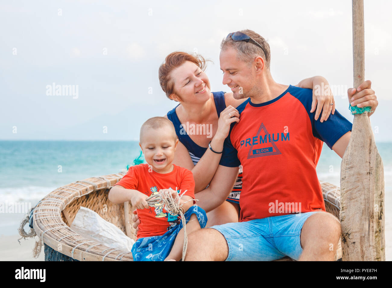 Famille dans un bateau avec une pagaie sur la plage. Banque D'Images