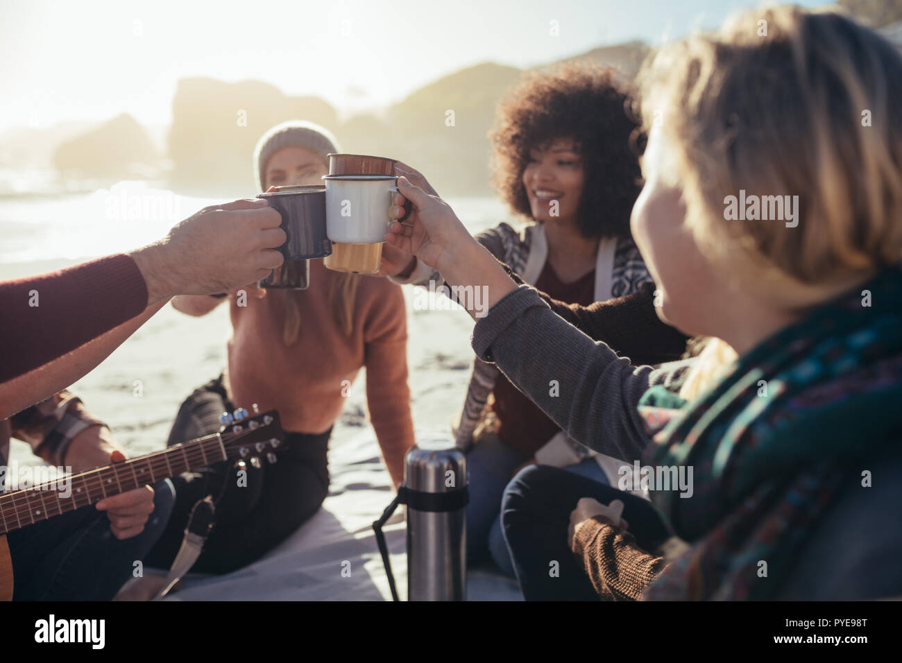 Groupe d'hommes et de femmes toasting tasses à café à la plage. Les amis à faire la fête dans la plage le café. Banque D'Images