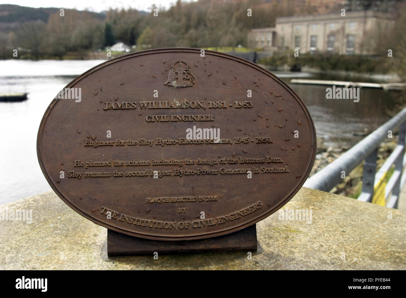 Un signe de bronze est situé en face de la station hydro-électrique de Sloy, dans l'arrière-plan, donne des détails et d'informations sur la station et comment il est venu à être, Loch Lomond, Ecosse . Banque D'Images