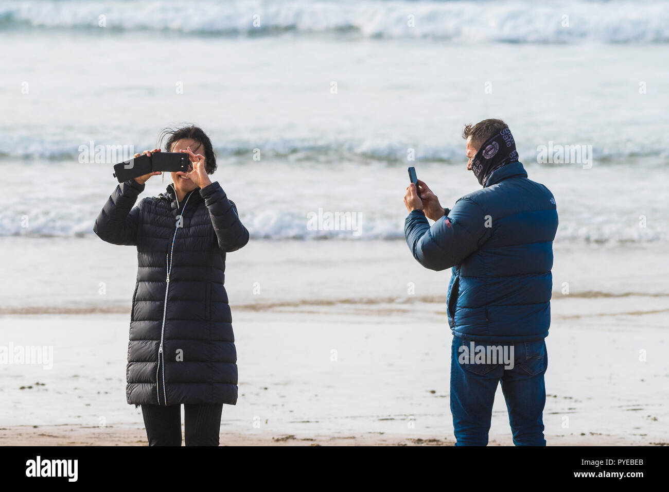 Deux vacanciers en utilisant leur smartphone pour photographier la plage de Fistral à Newquay en Cornouailles Banque D'Images