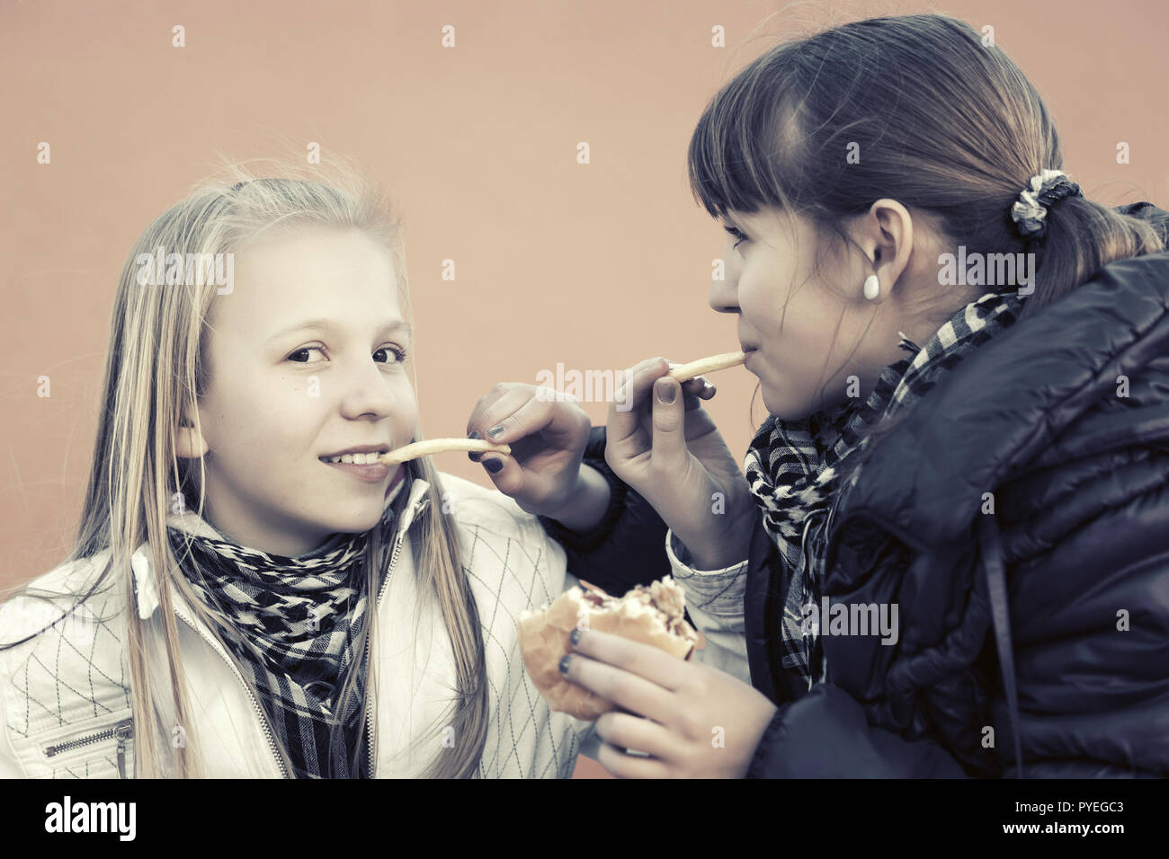 Happy teen girls eating burgers et libère un français Banque D'Images