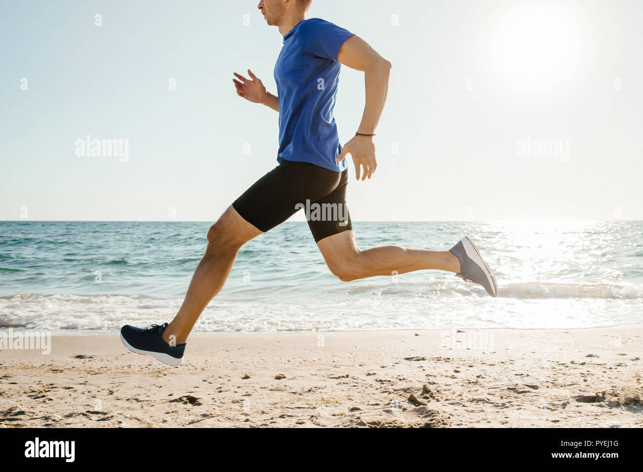 Homme runner le long de plage dans la lumière du soleil Banque D'Images