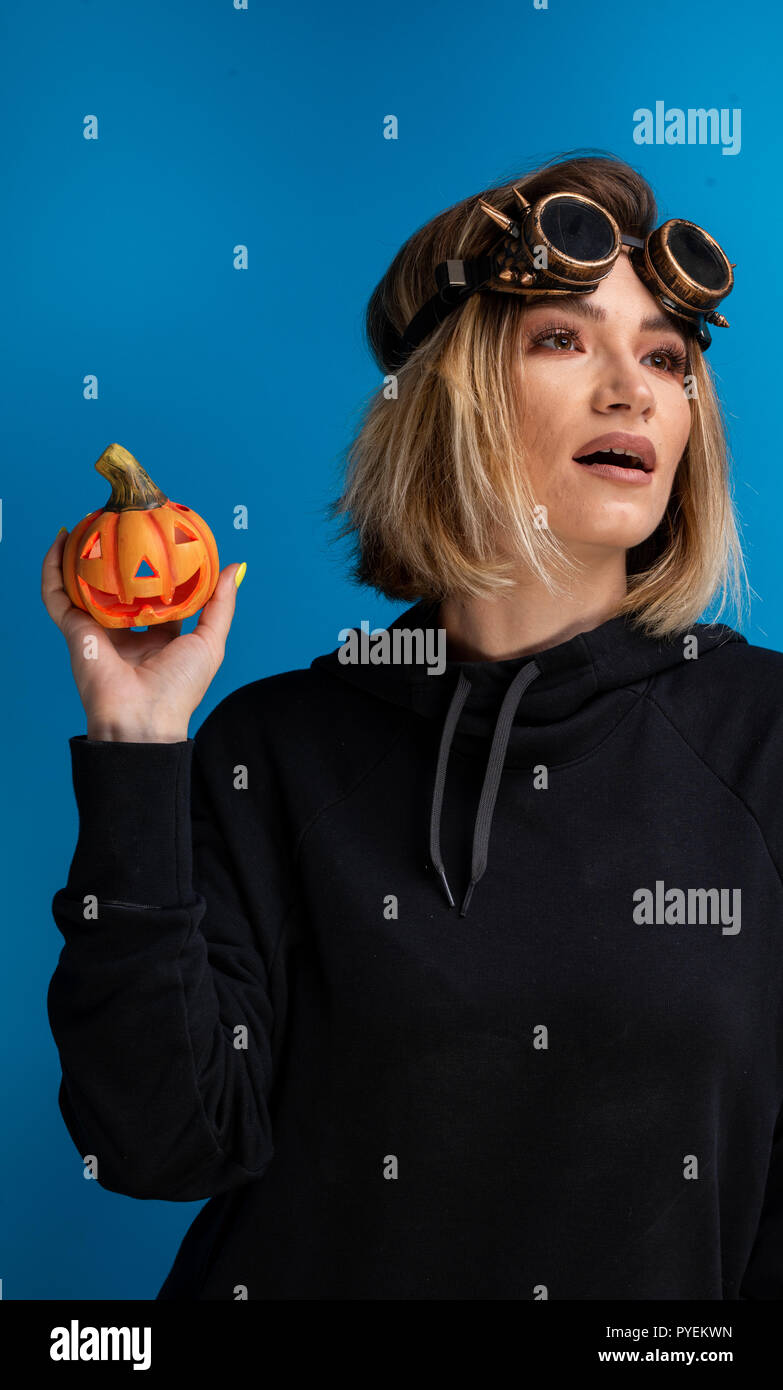 Portrait de la vapeur punk girl holding up un Halloween citrouille sculptée. Femme la mode goth hip-hop Banque D'Images