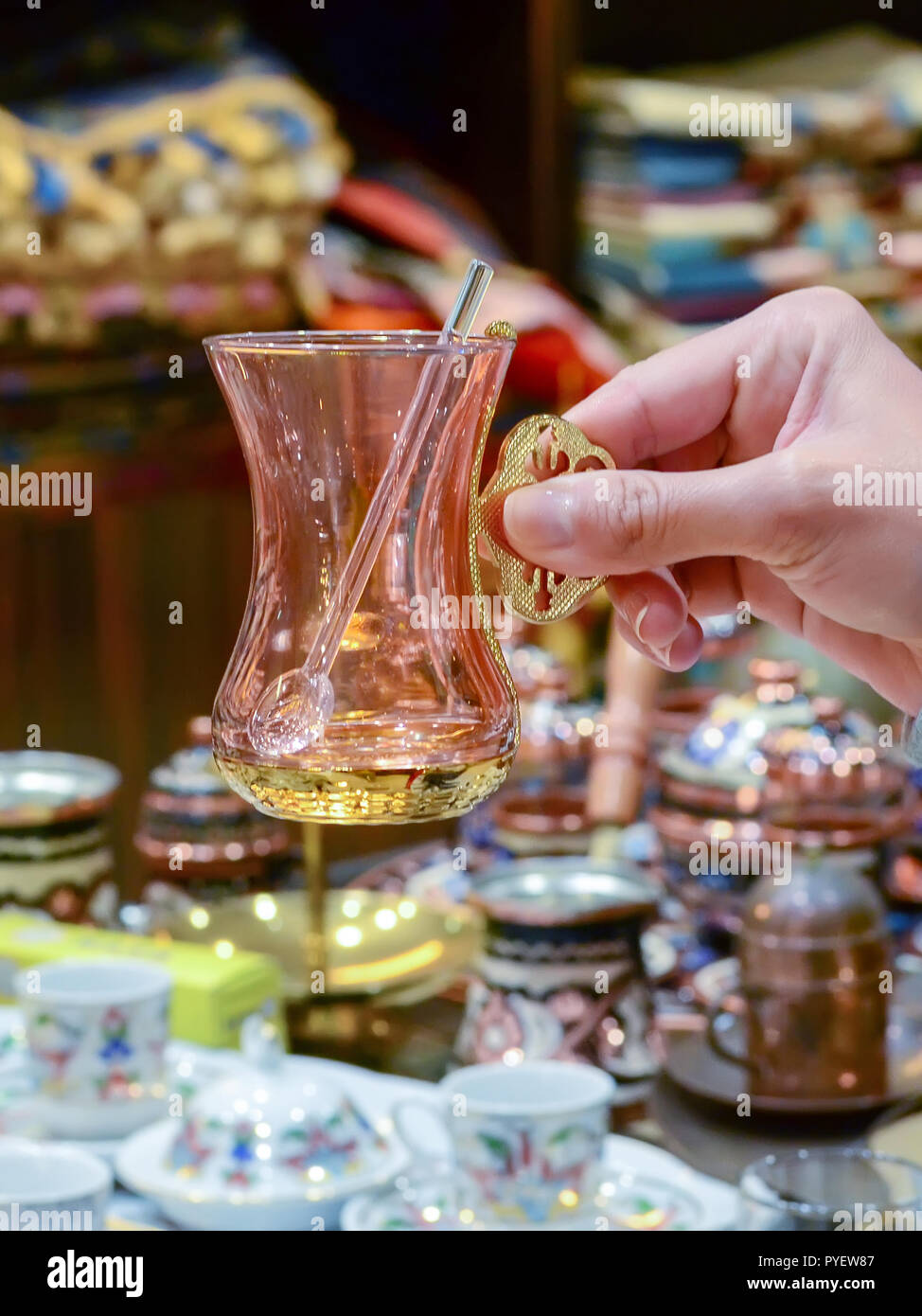 La main féminine est titulaire d'un verre de thé turc de souvenirs avec une cuillère. Banque D'Images