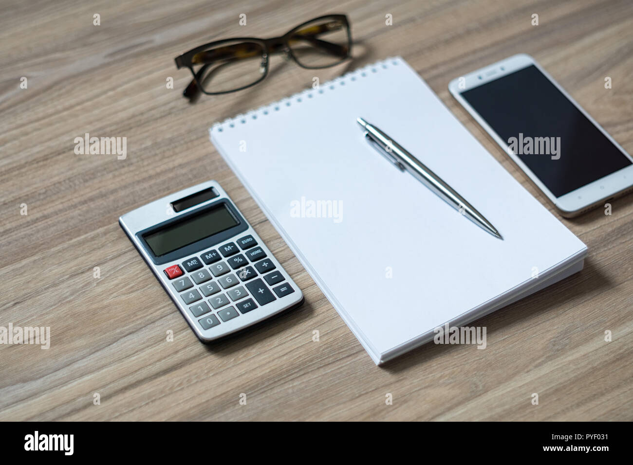 Le bloc-notes, calculatrice, smartphone, verres et silver sur stylo-bille meubles de bureau en bureau. Copie de l'image avec l'espace. Focus sélectif. Banque D'Images