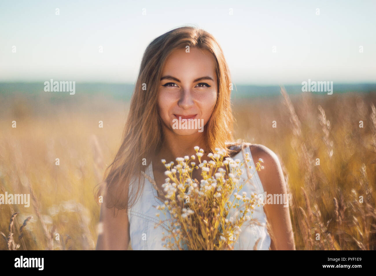 Attractive young woman standing in the meadow en jean sans manches à la robe d'été à huis clos Banque D'Images
