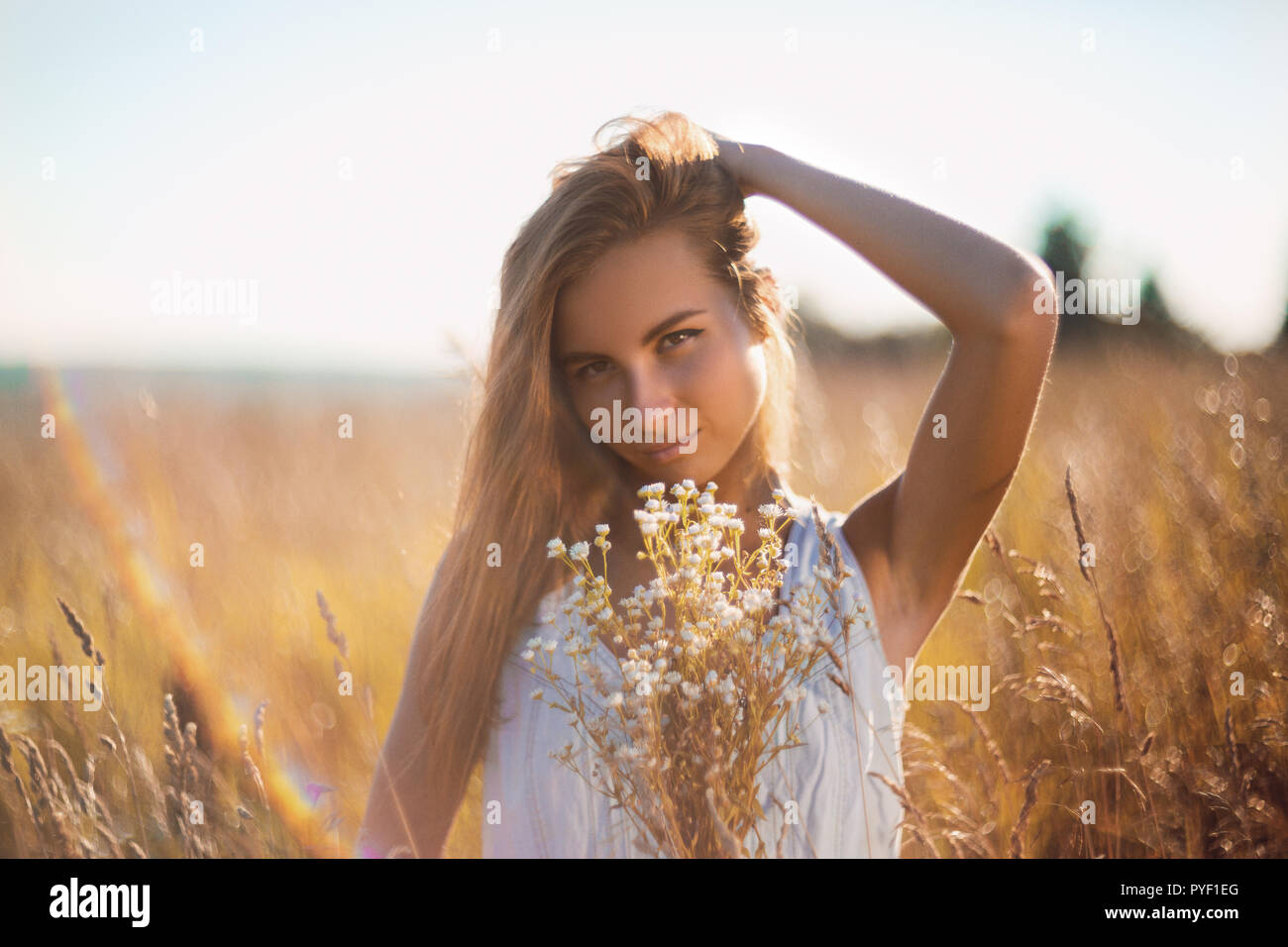 Attractive young woman standing in the meadow en jean sans manches robe d'été de remettre ses longs cheveux Banque D'Images