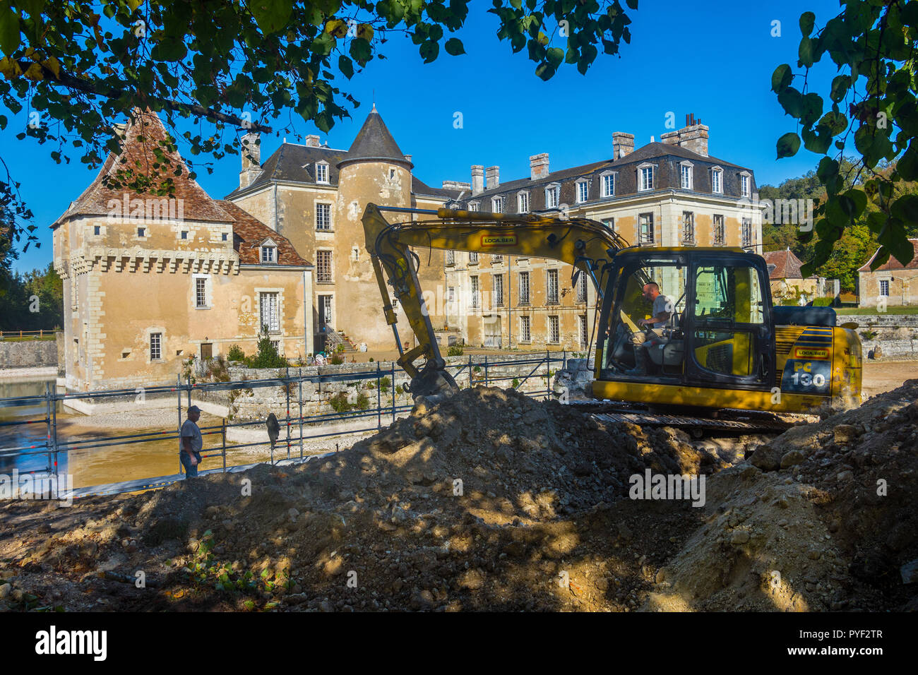 Les roches de la terre et de l'écopage Digger durant la réparation de mur de douves, le château de Boussay, France. Banque D'Images