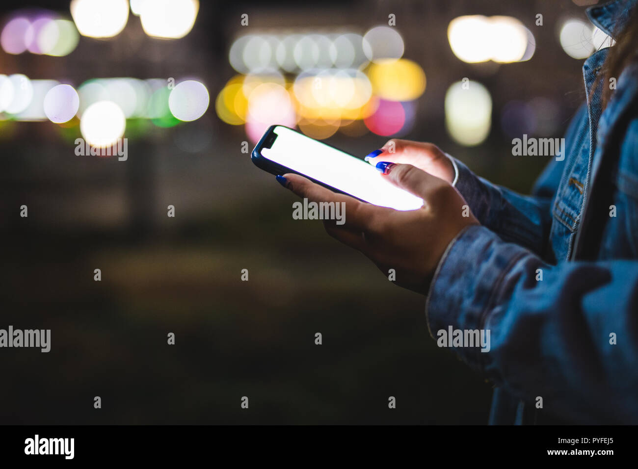 Femme doigt sur l'écran vierge du smartphone sur le flou d'arrière-plan de la lumière dans l'atmosphère de nuit, ville à l'aide dans les mains propres hipster gadget mobile phone Banque D'Images