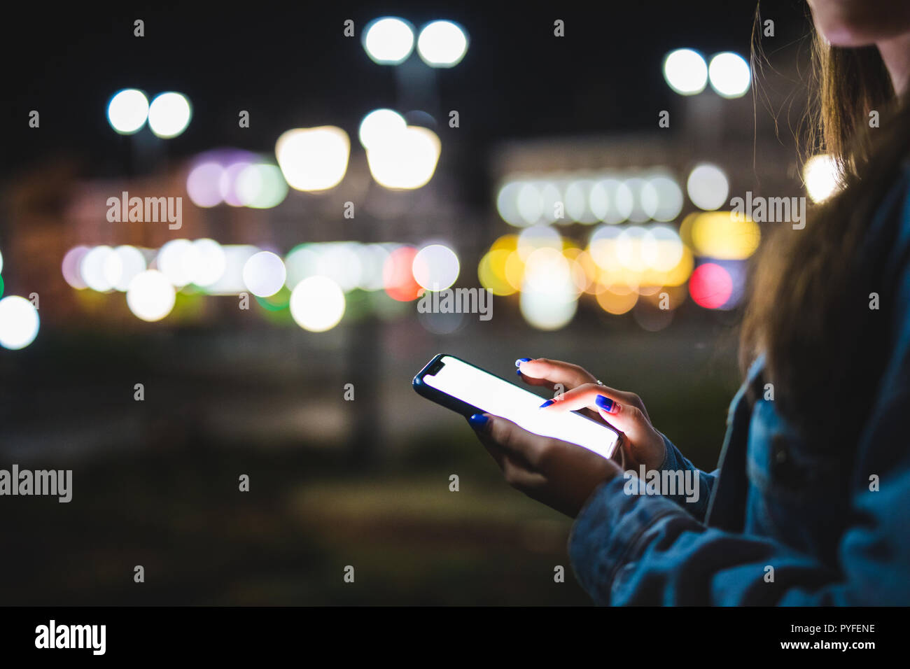 Femme doigt sur l'écran vierge du smartphone sur le flou d'arrière-plan de la lumière dans l'atmosphère de nuit, ville à l'aide dans les mains propres hipster gadget mobile phone Banque D'Images
