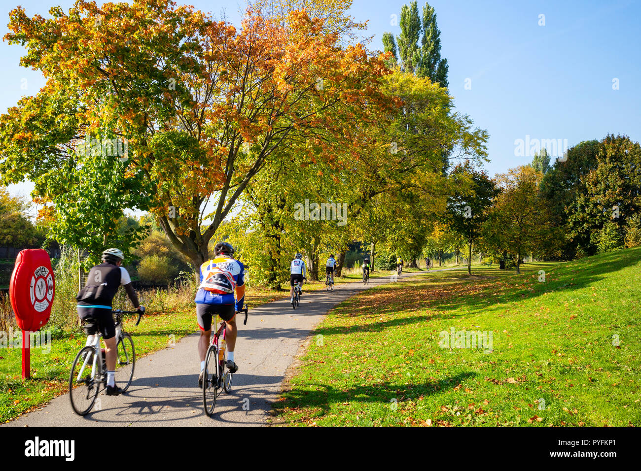 Les cyclistes qui profitent d'une journée ensoleillée d'automne au bord de la rivière Ouse dans York, Yorkshire, UK Banque D'Images