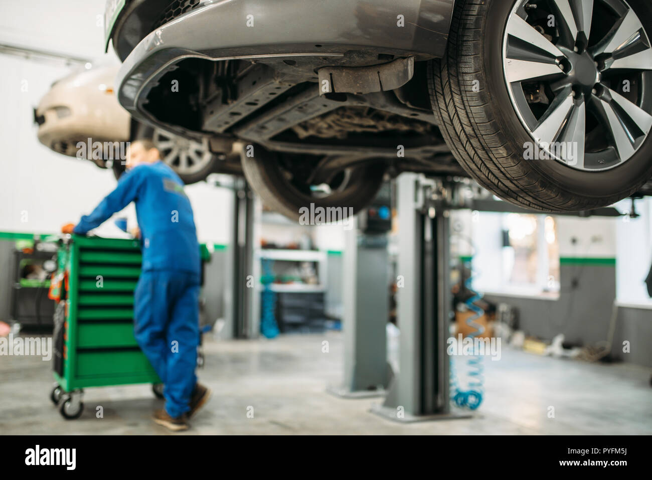 Réparateur en uniforme près de tool box contre une voiture sur l'ascenseur, de diagnostic de la suspension. Service de l'automobile, de l'entretien des véhicules Banque D'Images Réparateur en uniforme près de tool box contre une voiture sur l'ascenseur, de diagnostic de la suspension. Service de l'automobile, de l'entretien des véhicules Banque D'Images