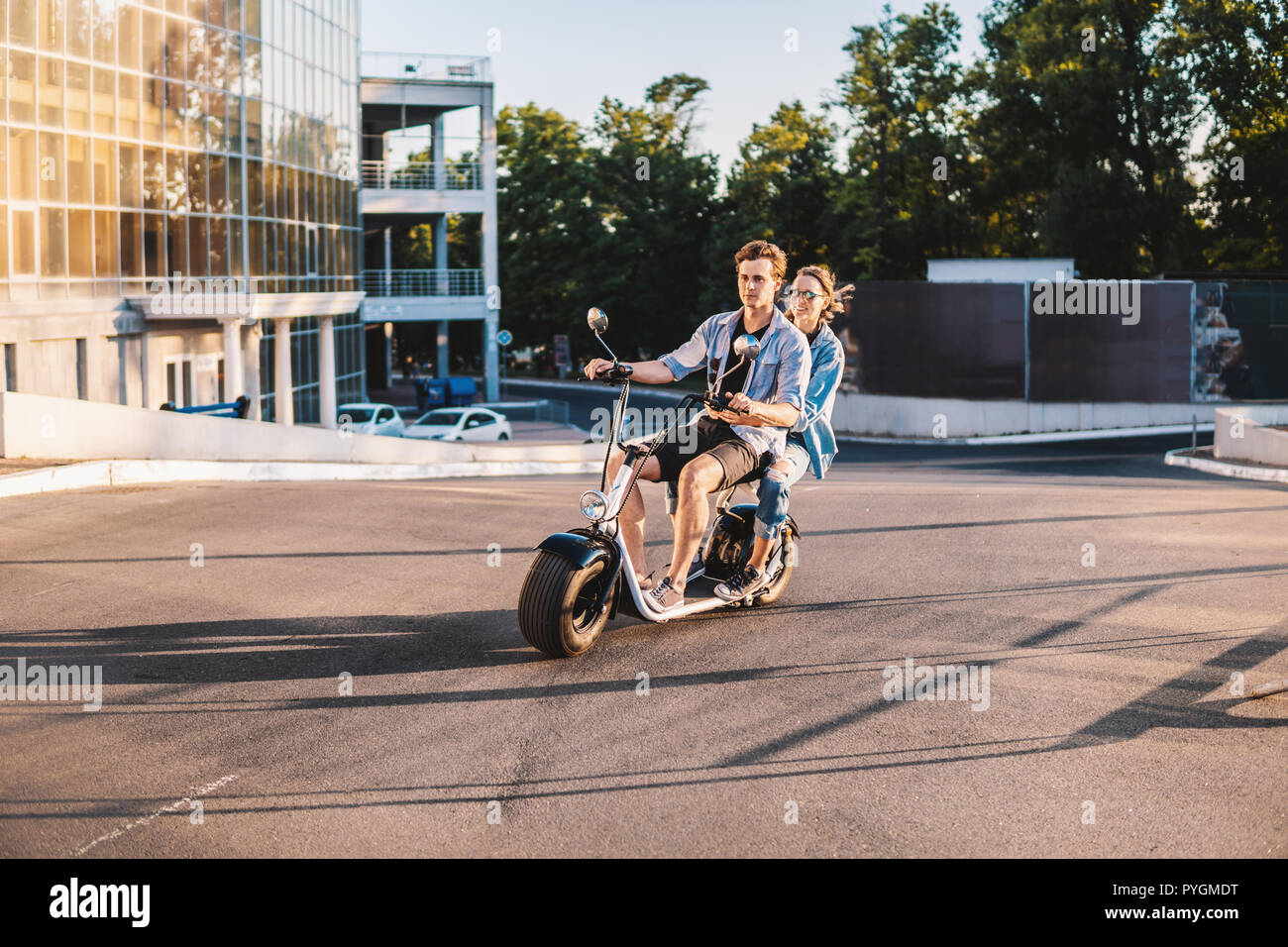 Charmante jeune couple heureux roulant vélo électrique Banque D'Images