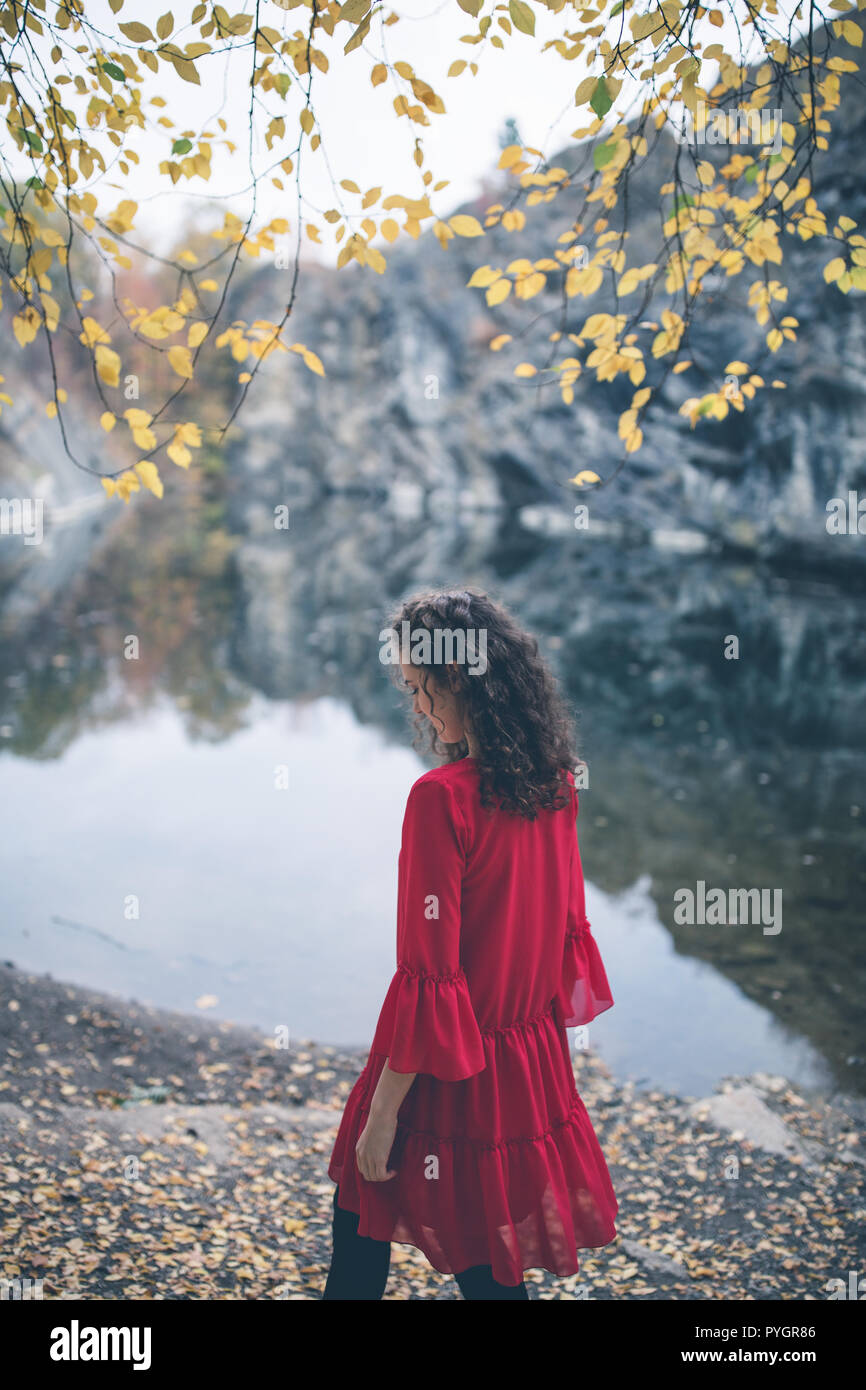 De beaux cheveux bouclés fille dans une robe rouge à pied par le lac.  Automne fond de rêve. Balades romantiques concept Photo Stock - Alamy