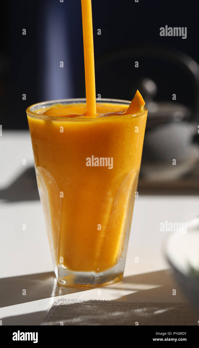 Photo macro d'un délicieux smoothie banane et mangue sur une table éclairée par le soleil Banque D'Images