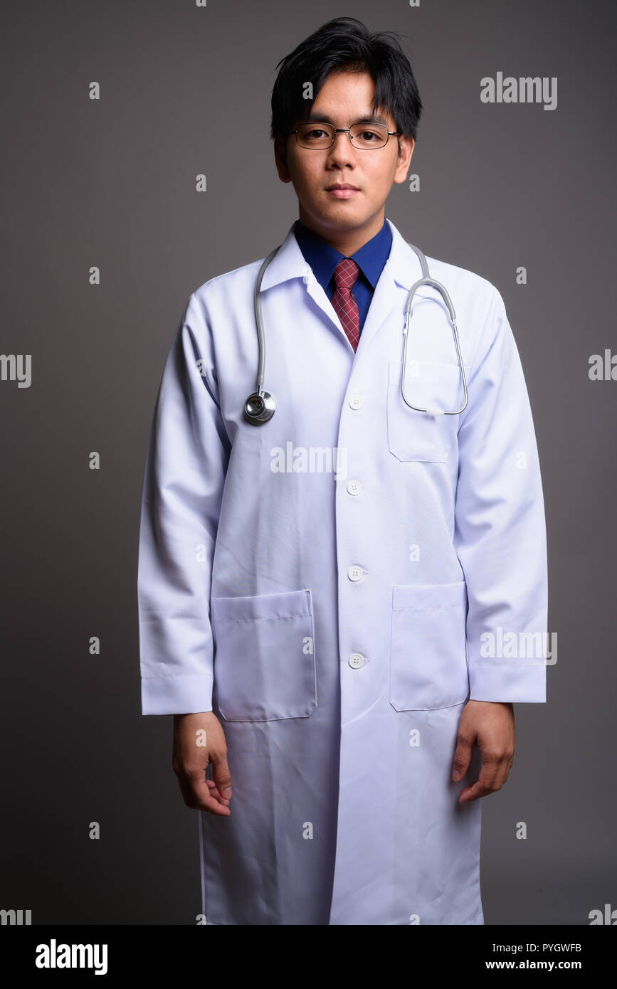 Portrait of young Asian man médecin contre l'arrière-plan gris Banque D'Images