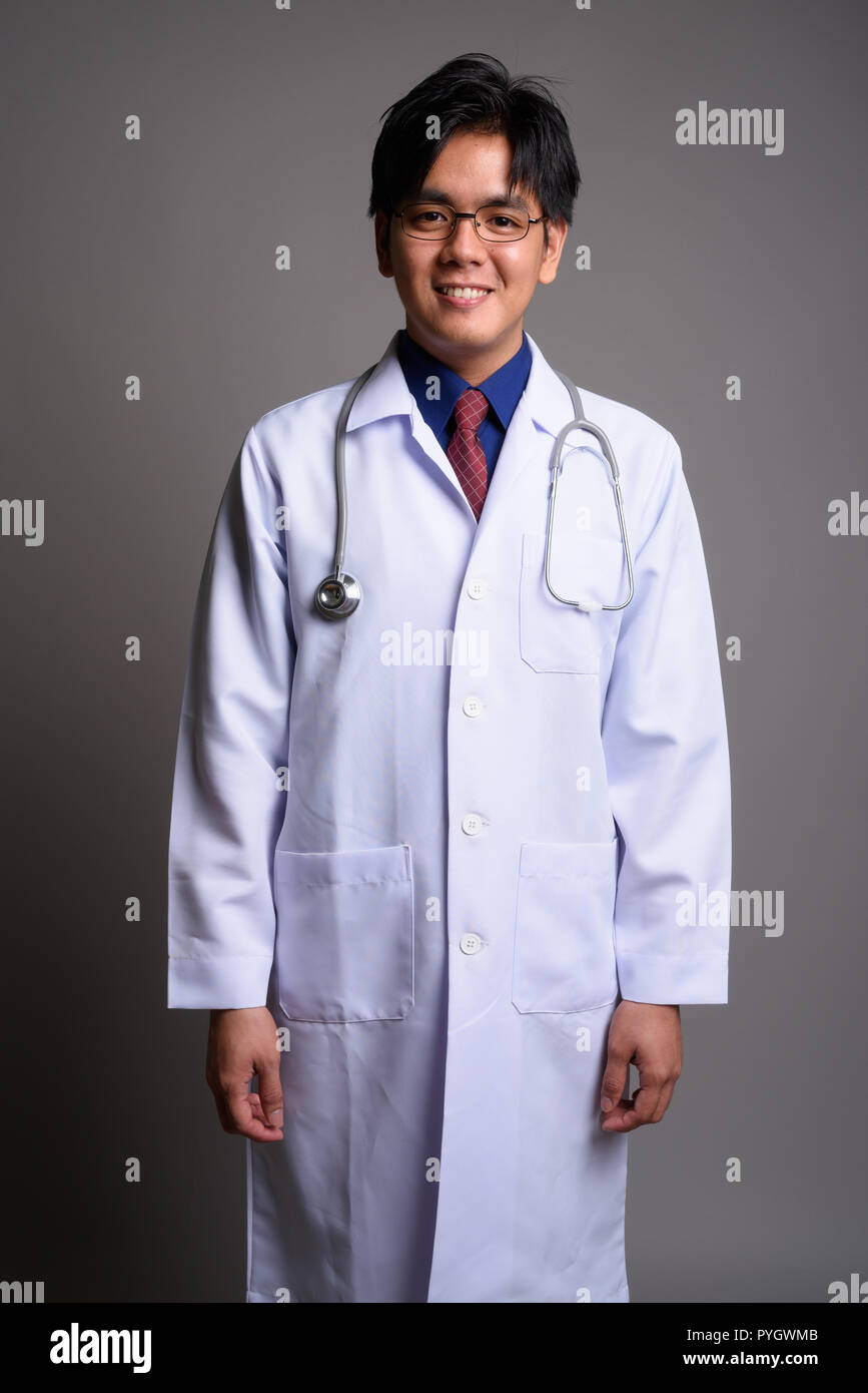 Happy Young Asian man smiling médecin contre l'arrière-plan gris Banque D'Images