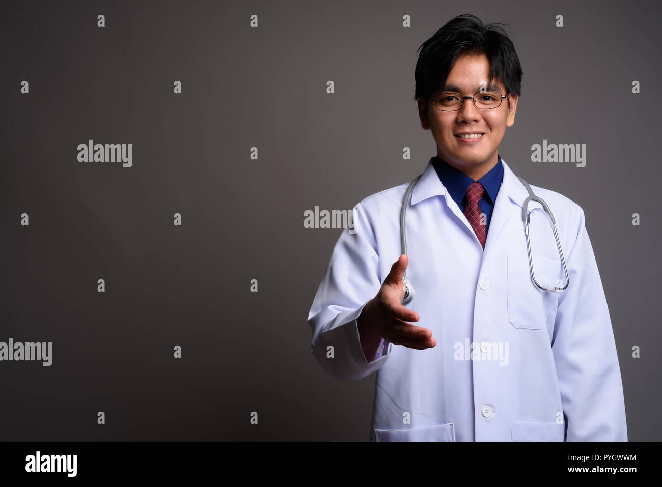Portrait of happy Young Asian man doctor giving handshake Banque D'Images