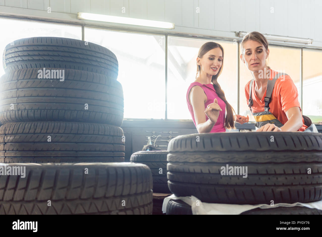 Mécanicien automobile féminin utile de vérifier le numéro d'identification du pneu Banque D'Images