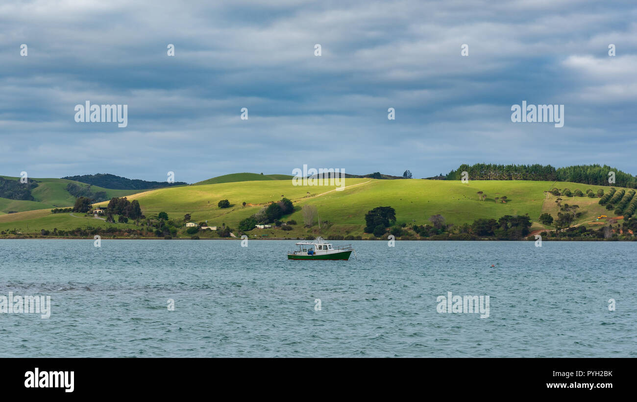 Vue sur la mer avec un patch de la lumière du soleil frappe une prairie avec un bateau de pêche dans l'avant-plan Banque D'Images