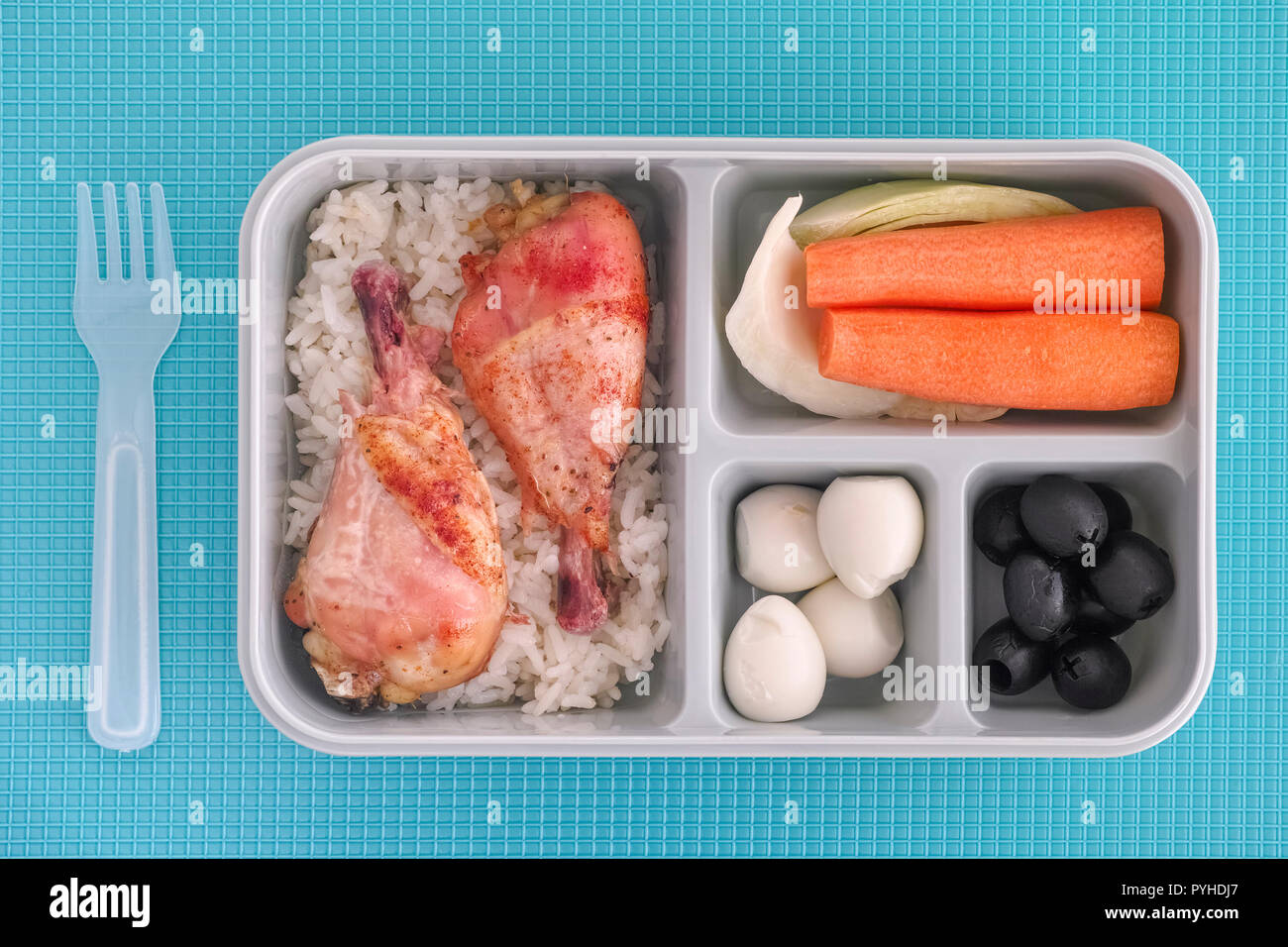 Boîte à lunch avec le riz et le poulet, œufs de caille, des olives noires et des légumes. Vue d'en haut. L'éclairage naturel. Close up. Banque D'Images