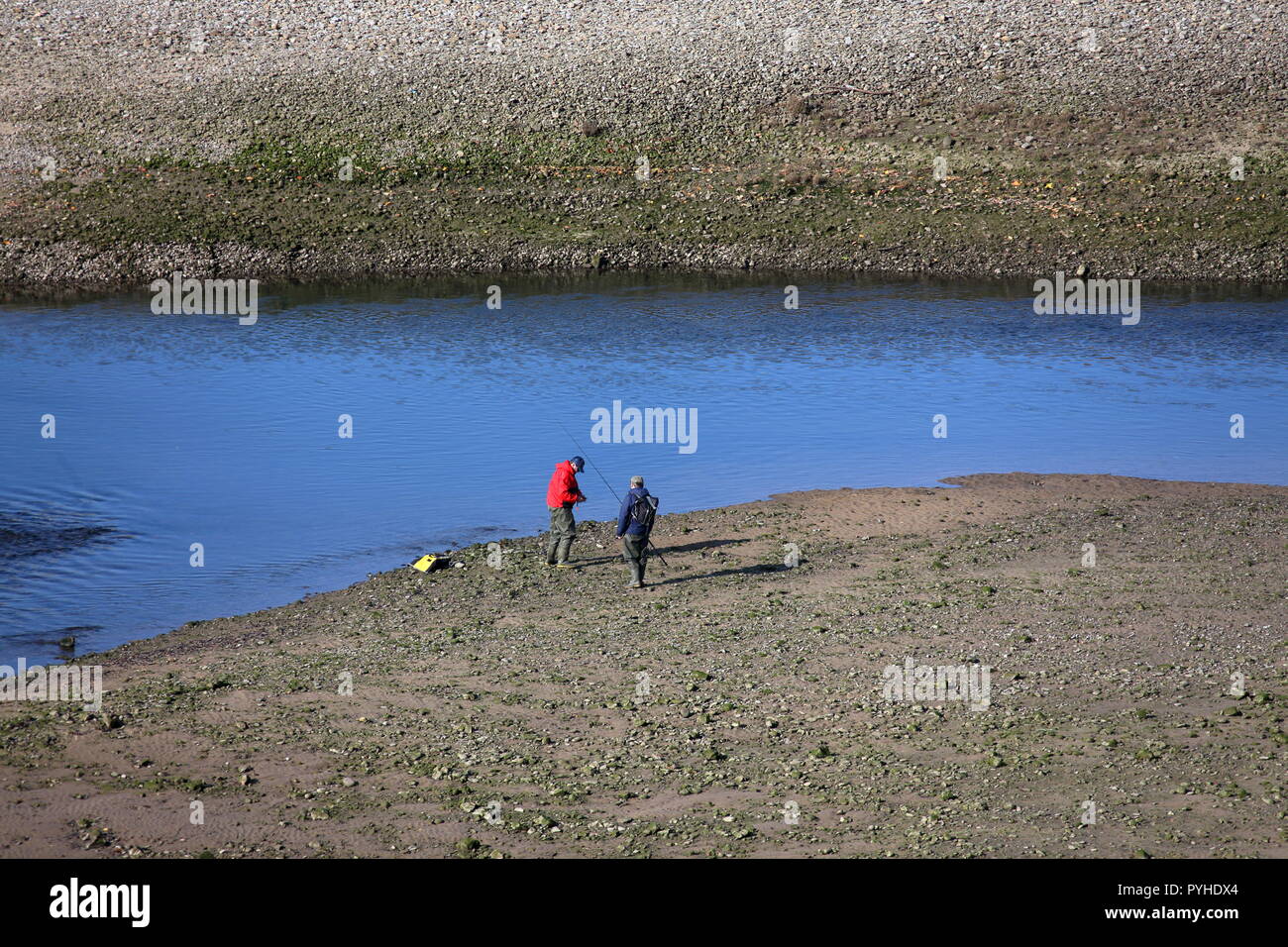 Deux pêcheurs à la mer grave à un bon endroit pour pêcher dans les marées rivermouth zone sur une journée ensoleillée en octobre sur le virage sur l'rivermouth à Ogmore. Banque D'Images