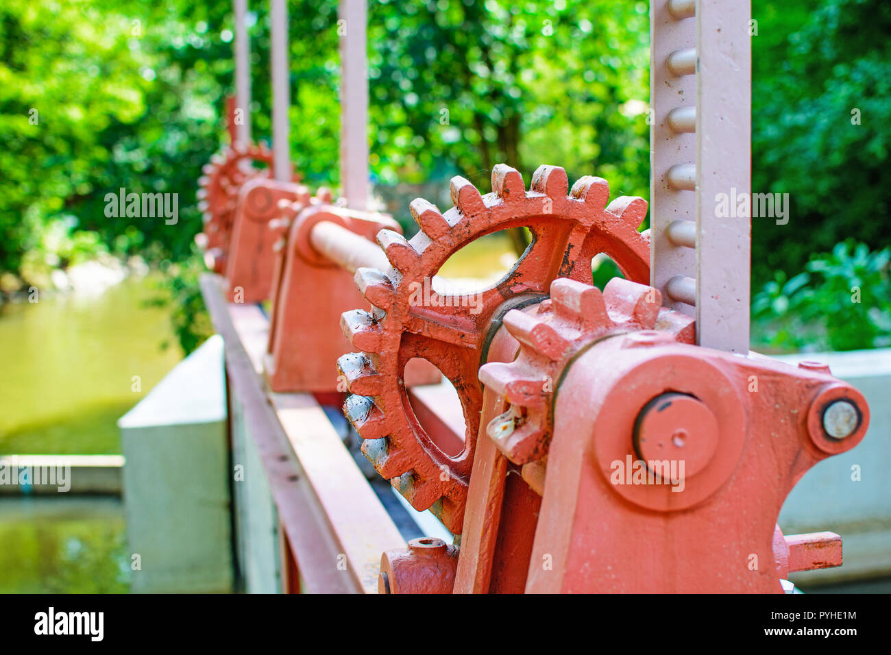 Close-up of a red metal gear sur la vanne. Mécanisme d'ouverture du barrage. Vieille roue dentée sur la rivière. Transfert à l'ouverture du barrage. Vieux cogw Banque D'Images